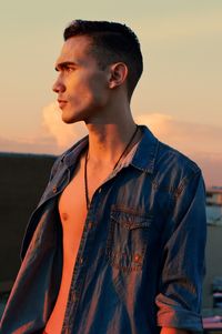 Young man standing against sky during sunset