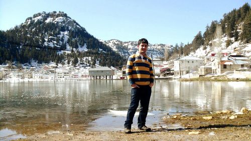 Portrait of man at lakeshore against mountains