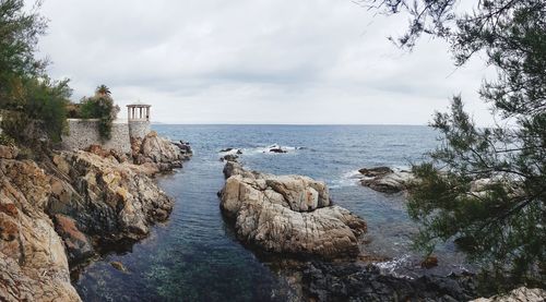 Panoramic shot of rocks in sea against sky