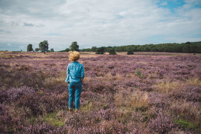 Rear view of woman walking on field against sky