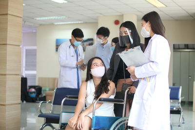 Cheerful doctors wearing mask sitting on wheelchair