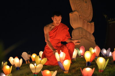 Man and illuminated candles on temple at night