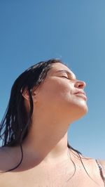 Low angle view of young woman behind blue sky with wet air