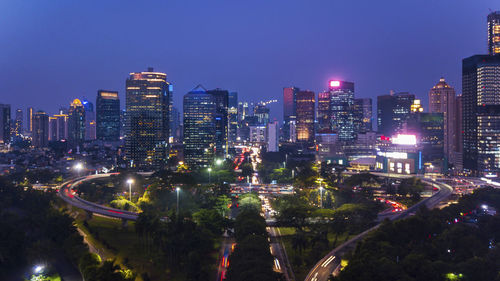 Illuminated buildings in city against clear sky at night