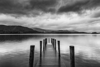 Wooden jetty in lake against sky