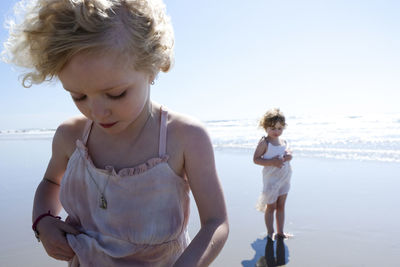 Sisters standing at beach against sky