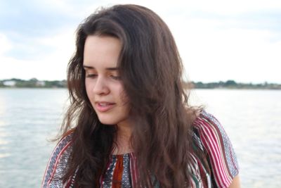 Portrait of beautiful young woman standing against sky