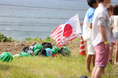 People standing by flags on grassy field