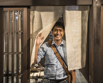 Man exiting a house in japan through traditional noren