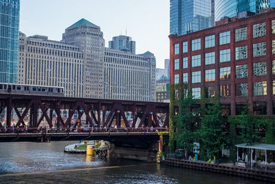 Bridge over river by buildings against sky in city