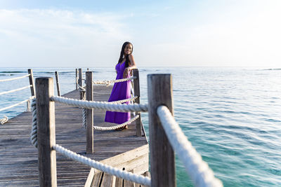 Side view of woman standing by a pier rope railing
