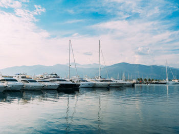 Sailboats moored in harbor against sky