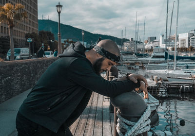 Side view of man with arms outstretched at harbor