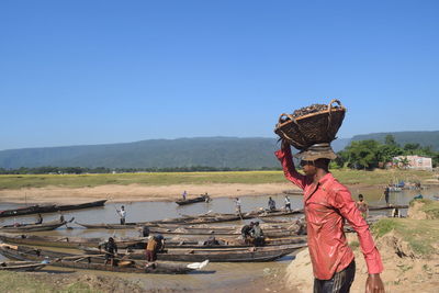 Man carrying basket on head against river