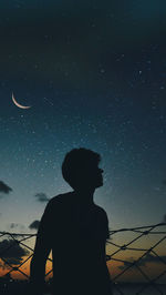 Low angle view of silhouette man standing against sky at night