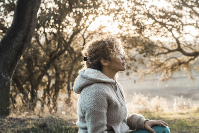 Side view of woman sitting on tree