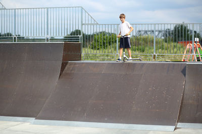 Active ten year old boy riding a scooter in the summer skate park