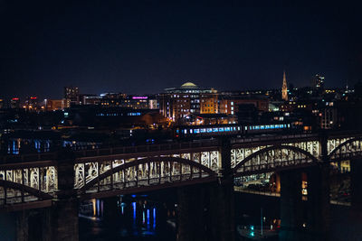 Illuminated buildings in newcastle at night with high level bridge in the foreground