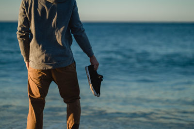 Rear midsection of man standing at beach