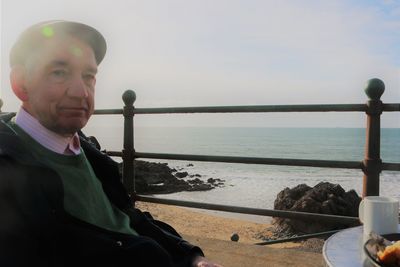 Portrait of man standing by sea against sky