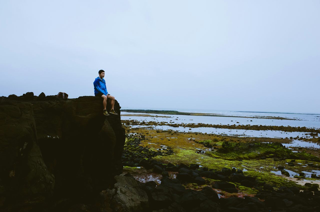 clear sky, copy space, lifestyles, leisure activity, full length, standing, men, casual clothing, water, rear view, nature, tranquility, tranquil scene, beauty in nature, scenics, blue, sky, sea