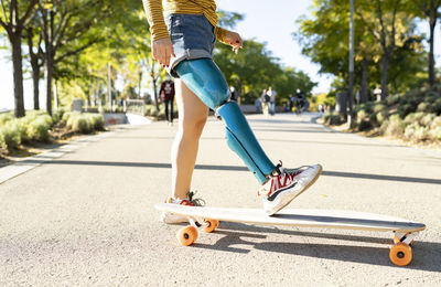 Low section of boy skateboarding on road