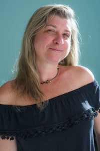 Portrait of a woman looking into the camera against a light green background. 