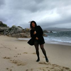 Portrait of happy woman standing at sandy beach