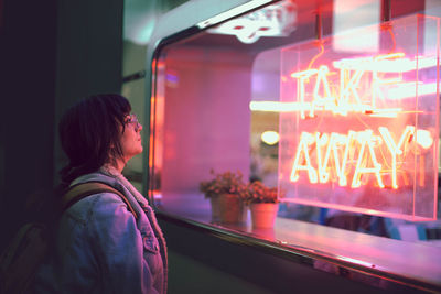 Rear view of man looking at illuminated store