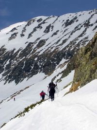 People on snowcapped mountain against sky