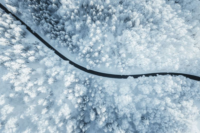 Wintery aerial view at road winding through forest covered in deep snow, austria.