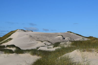 Scenic view of sand dunes against clear blue sky