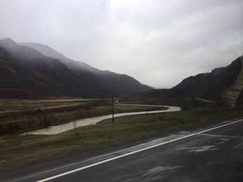 Scenic view of road and mountains against sky