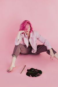 Young woman sitting over colored background