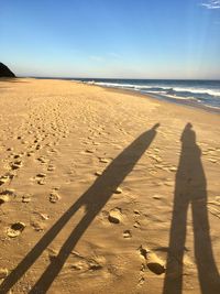 Shadow of people on beach against clear sky