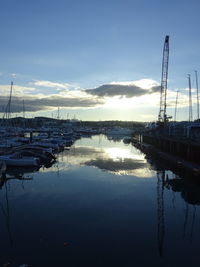 Boats moored in harbor at lake against sky