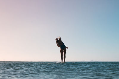 Full length of man standing in sea against clear sky