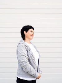 Portrait of smiling young woman standing against wall