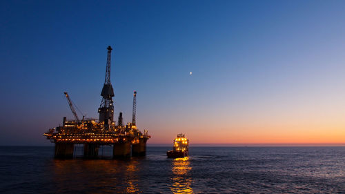 Illuminated ship in sea against clear sky