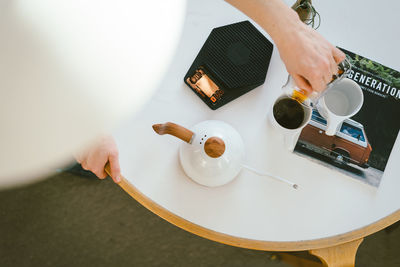 High angle view of hand holding coffee cup on table