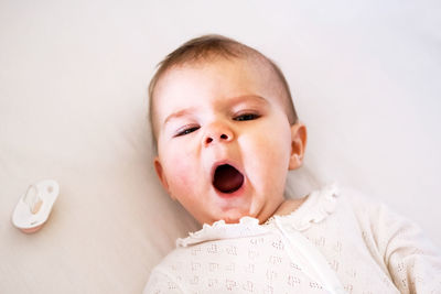 Adorable little baby girl is yawning on her bed before go to sleep.