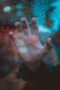 Close-up of human hand on wet glass window