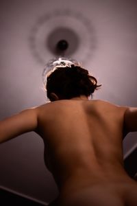 Rear view of shirtless woman looking at camera