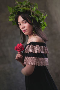 Portrait of beautiful woman standing by red rose