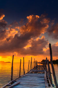 Pier over sea against orange sky