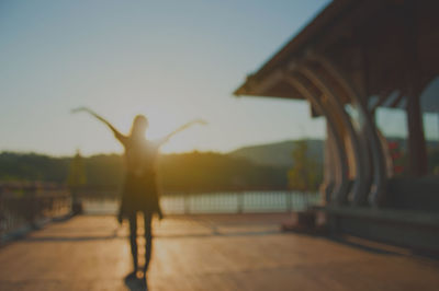 Rear view of woman standing against sky during sunset