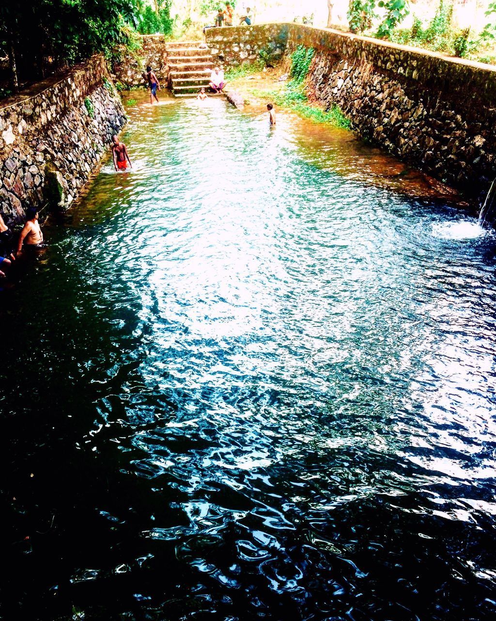 HIGH ANGLE VIEW OF PEOPLE SWIMMING IN WATER