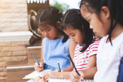 Girls studying while sitting on chair