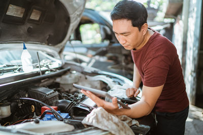 Side view of young man repairing car