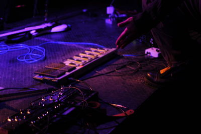 Midsection of dj by sound mixer at nightclub